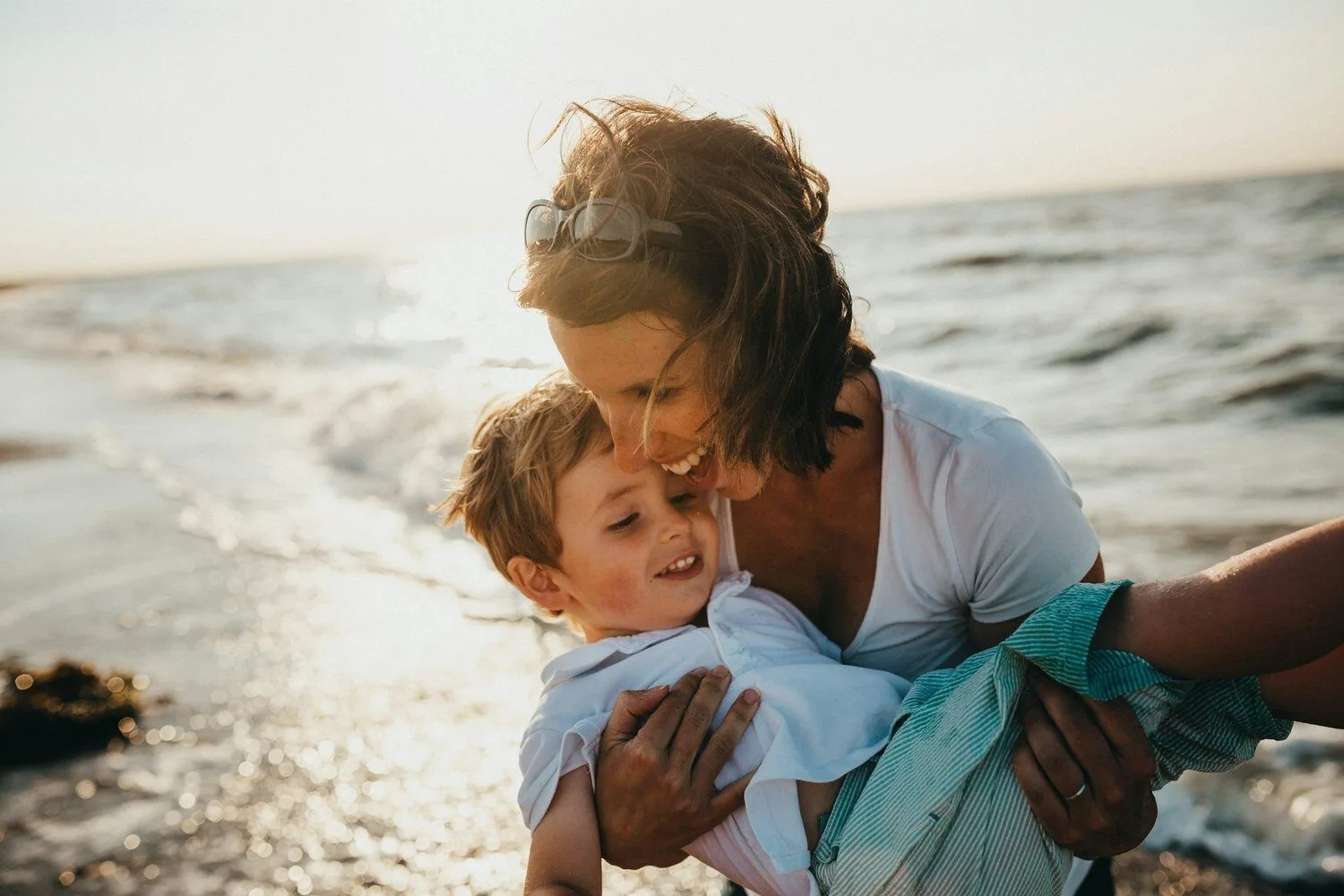 Kid on the beach with mom teaching him how to speak