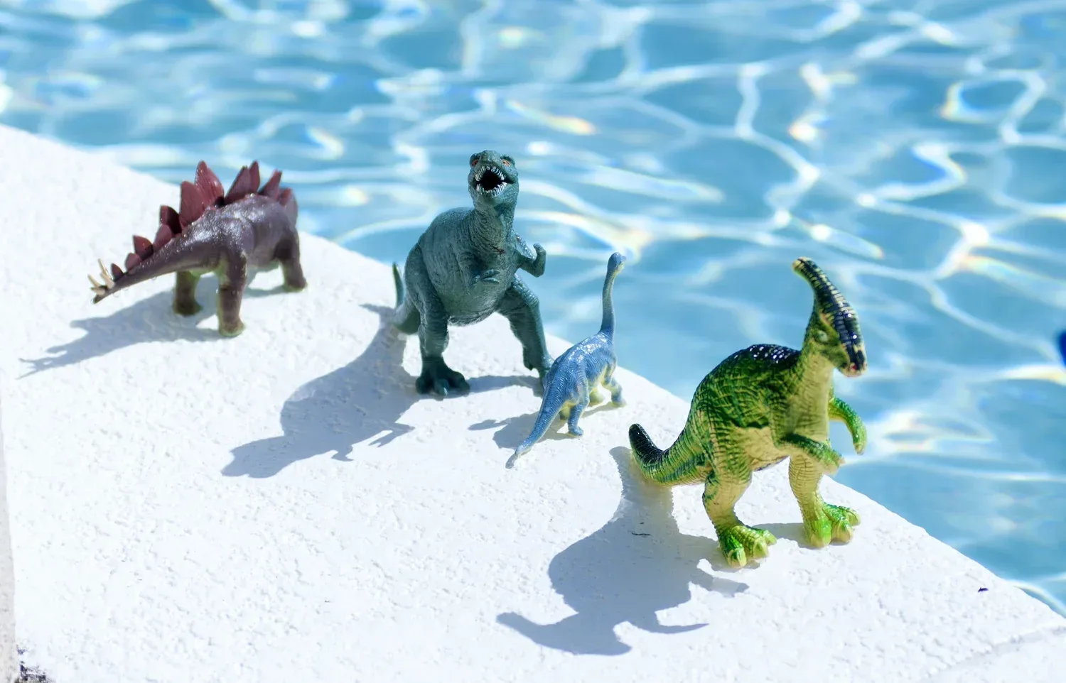 Toy dinosaurs near the edge of a pool during interest based speech pathology sessions in Encinitas CA
