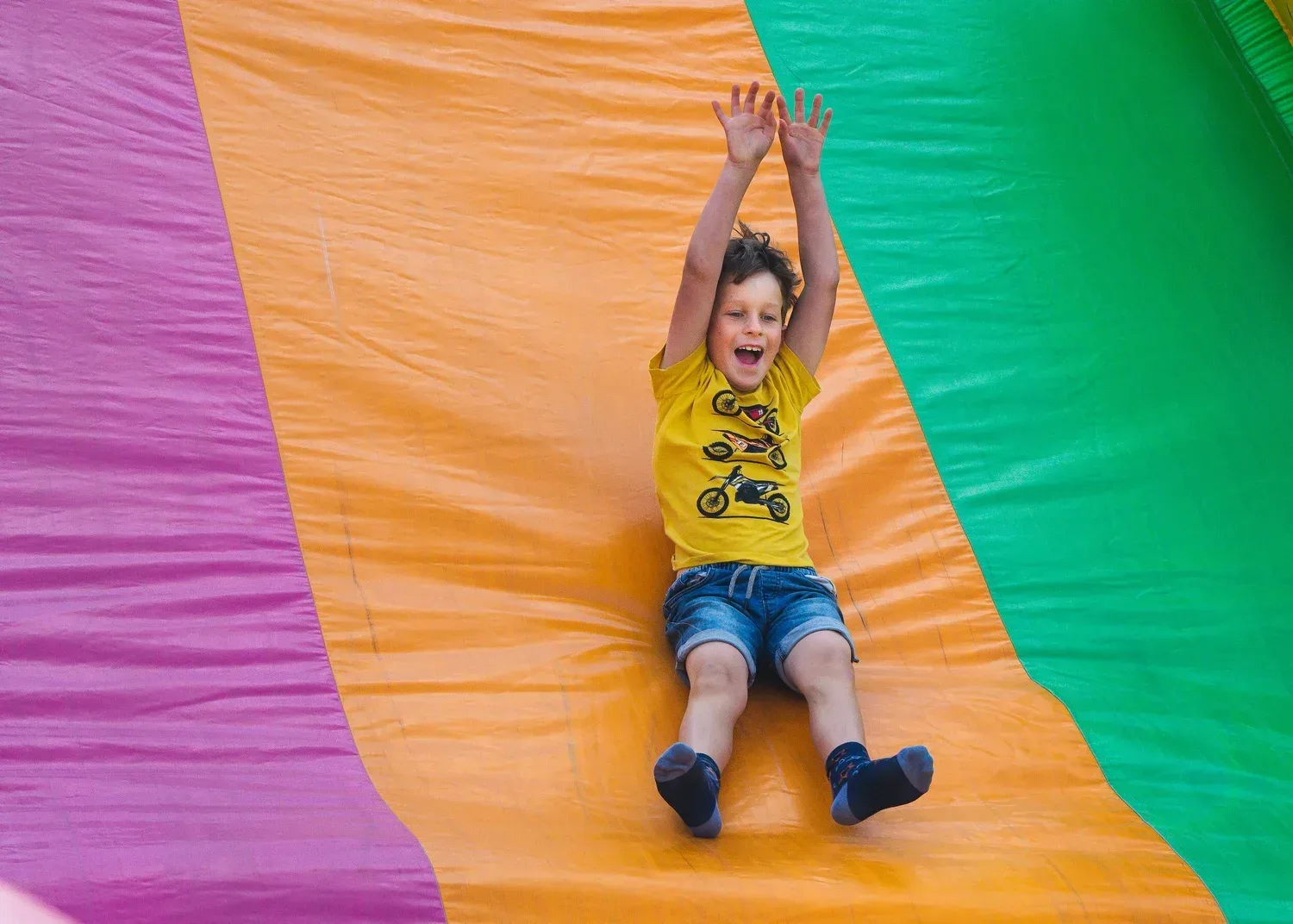 Child having fun with his hands in the air on a slide to show expression