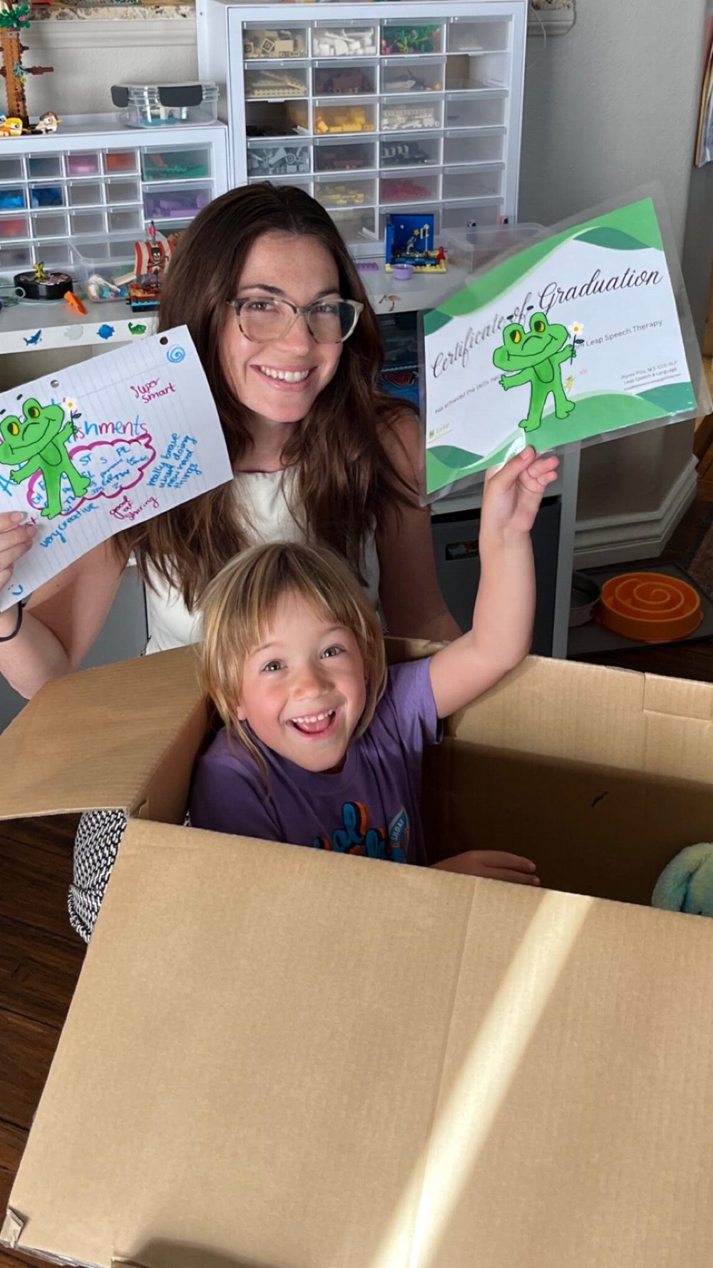 Speech therapist and smiling child holding up a Leap Speech Therapy certificate of graduation