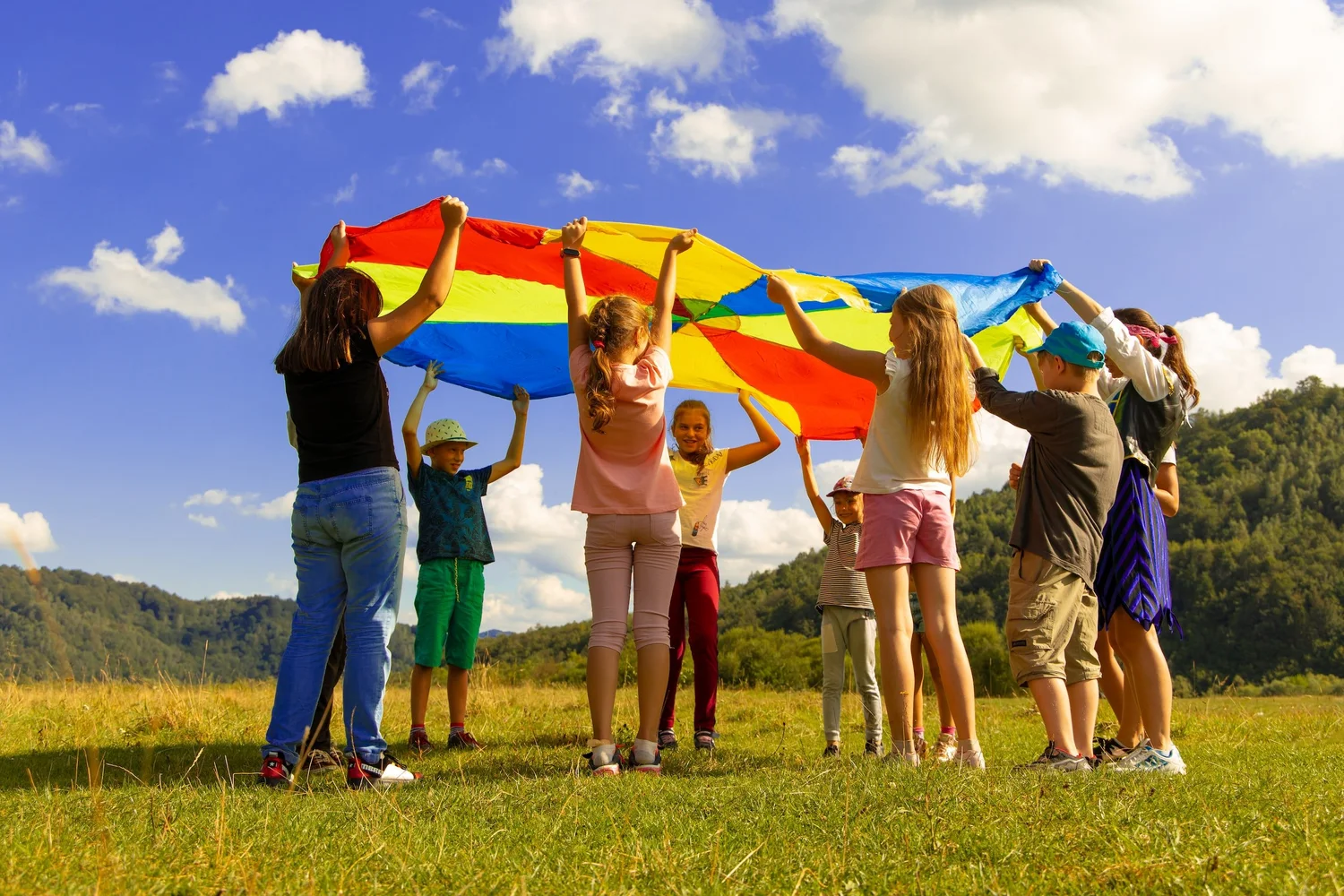 Children participating in outdoor parachute for speech therapy session play based in a field
